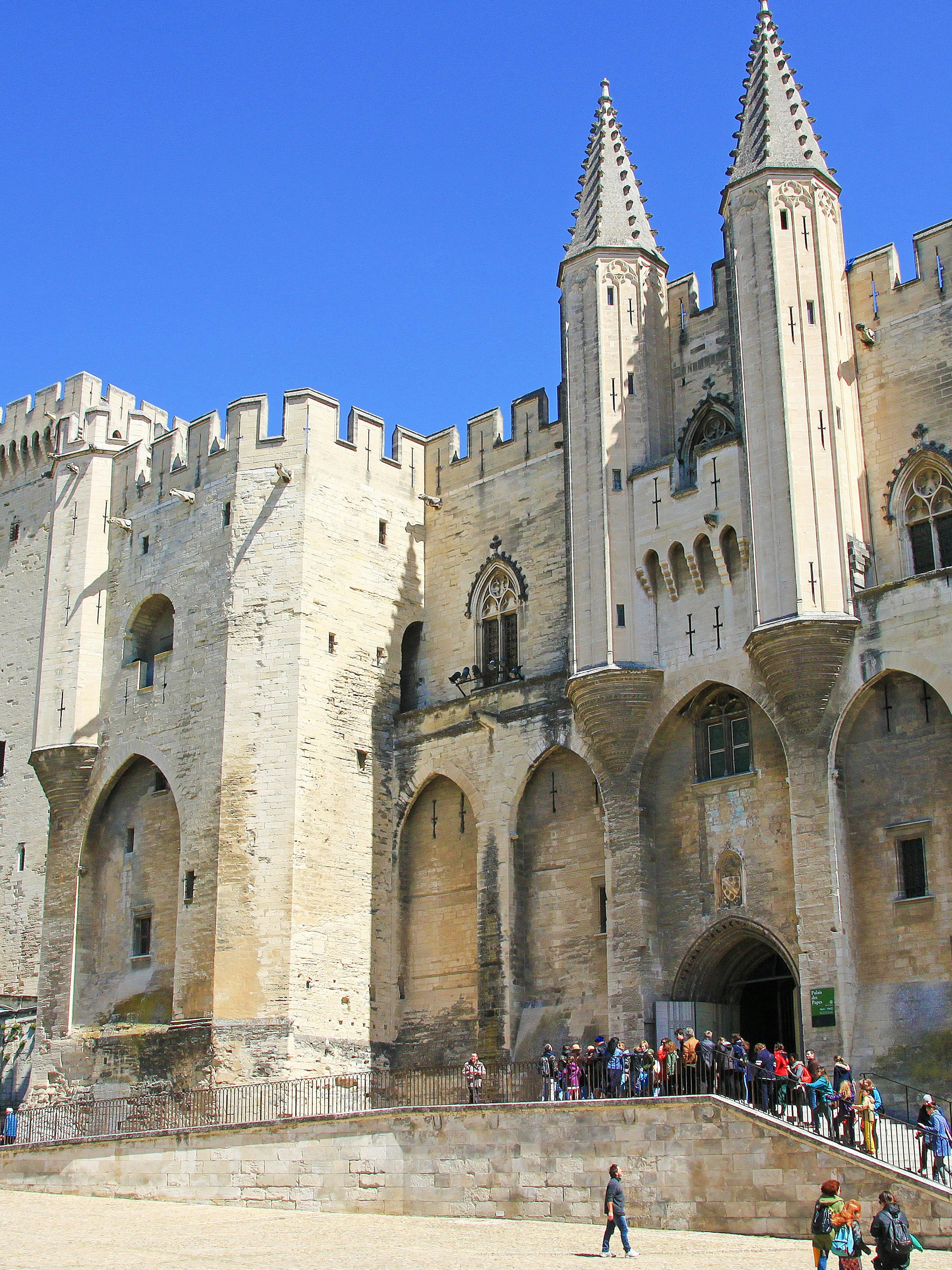 Popes Palace in Avignon with tourists exploring the historic architecture.