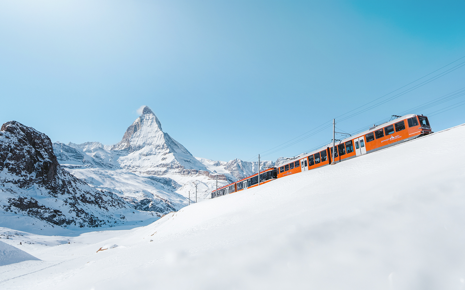 Glacier Express train crossing a scenic bridge in the Swiss Alps.