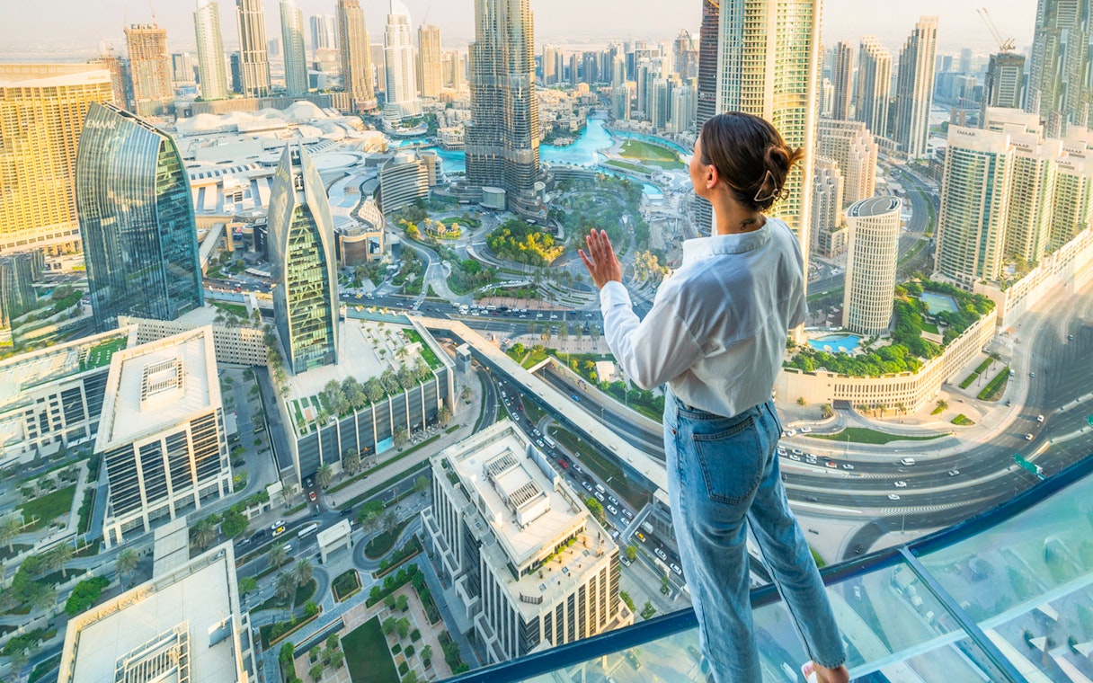 Person enjoying view from Sky Views Edge Walk, overlooking Dubai skyline and Burj Khalifa.