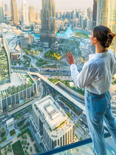 Person enjoying view from Sky Views Edge Walk, overlooking Dubai skyline and Burj Khalifa.