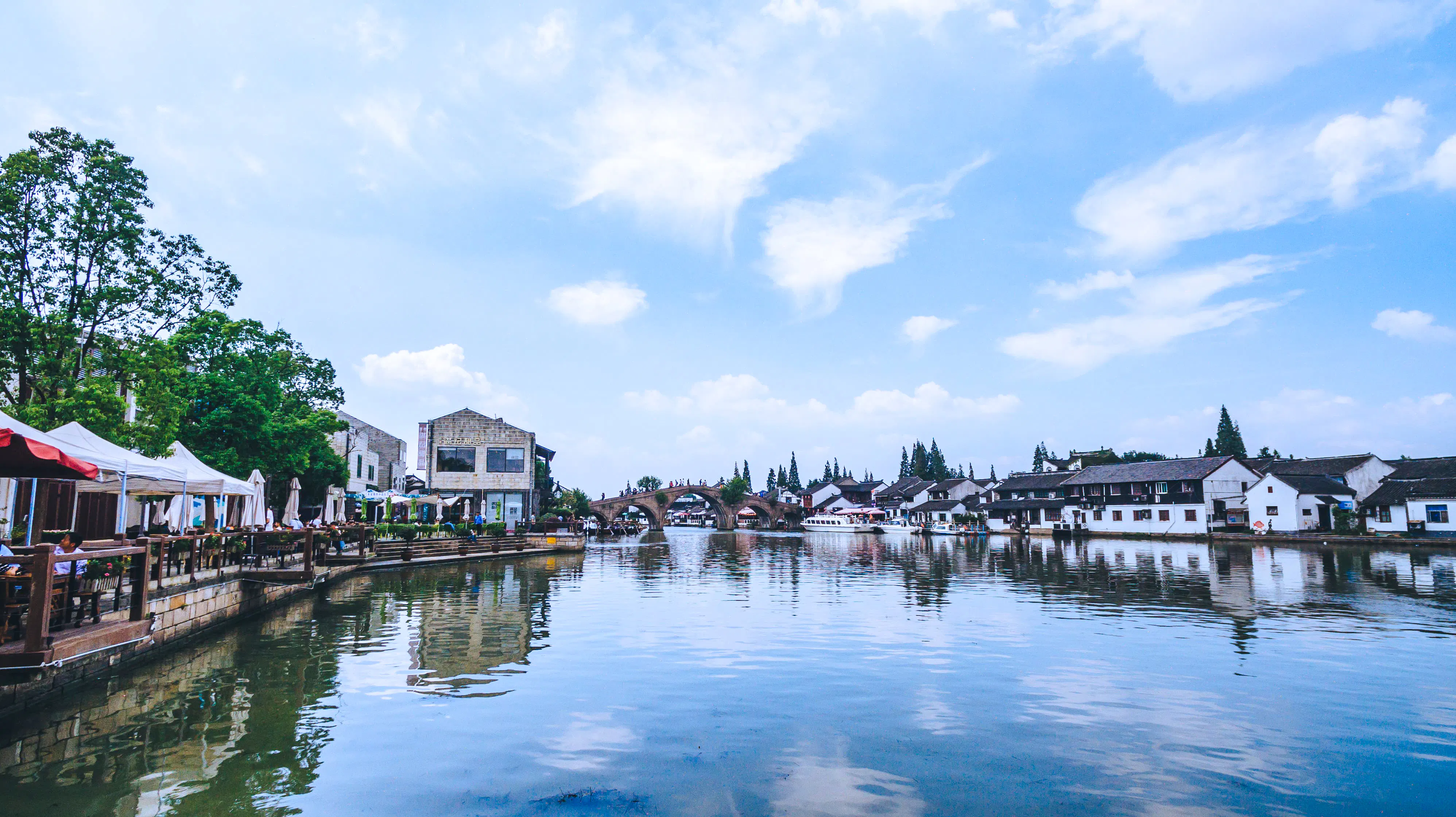 Waterfront view of traditional buildings and arched bridge in a Shanghai water town.