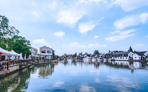 Waterfront view of traditional buildings and arched bridge in a Shanghai water town.