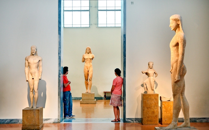 Visitors viewing ancient Greek statues at Athens National Archaeological Museum.