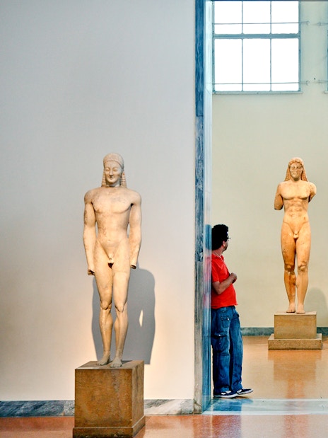 Visitors viewing ancient Greek statues at Athens National Archaeological Museum.