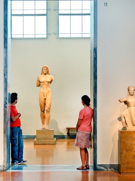Visitors viewing ancient Greek statues at Athens National Archaeological Museum.