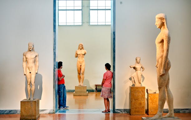Visitors viewing ancient Greek statues at Athens National Archaeological Museum.