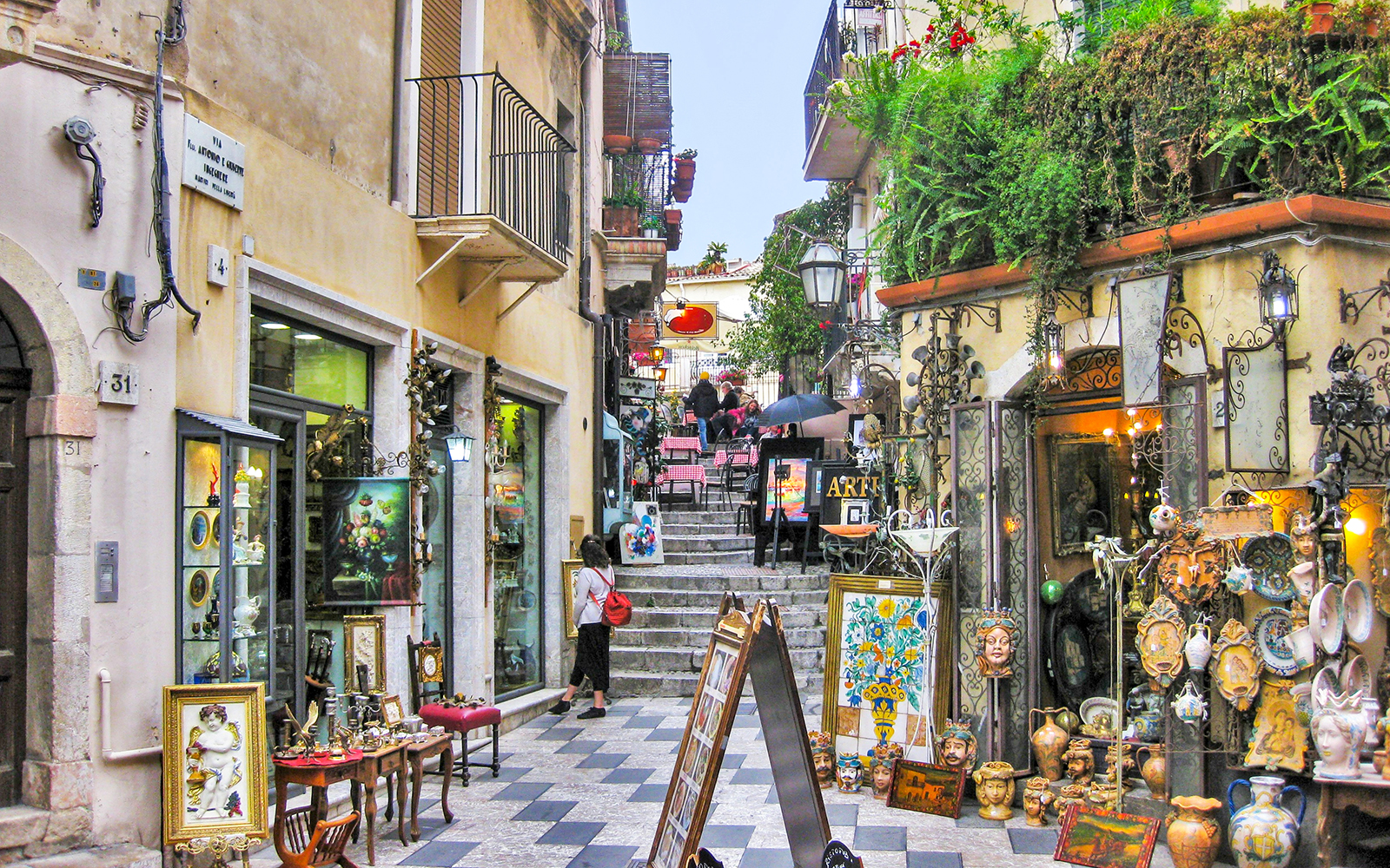 Taormina street with art shops and outdoor café, part of Messina to Taormina transfer experience.