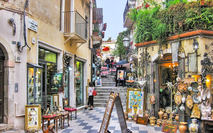 Taormina street with art shops and outdoor café, part of Messina to Taormina transfer experience.