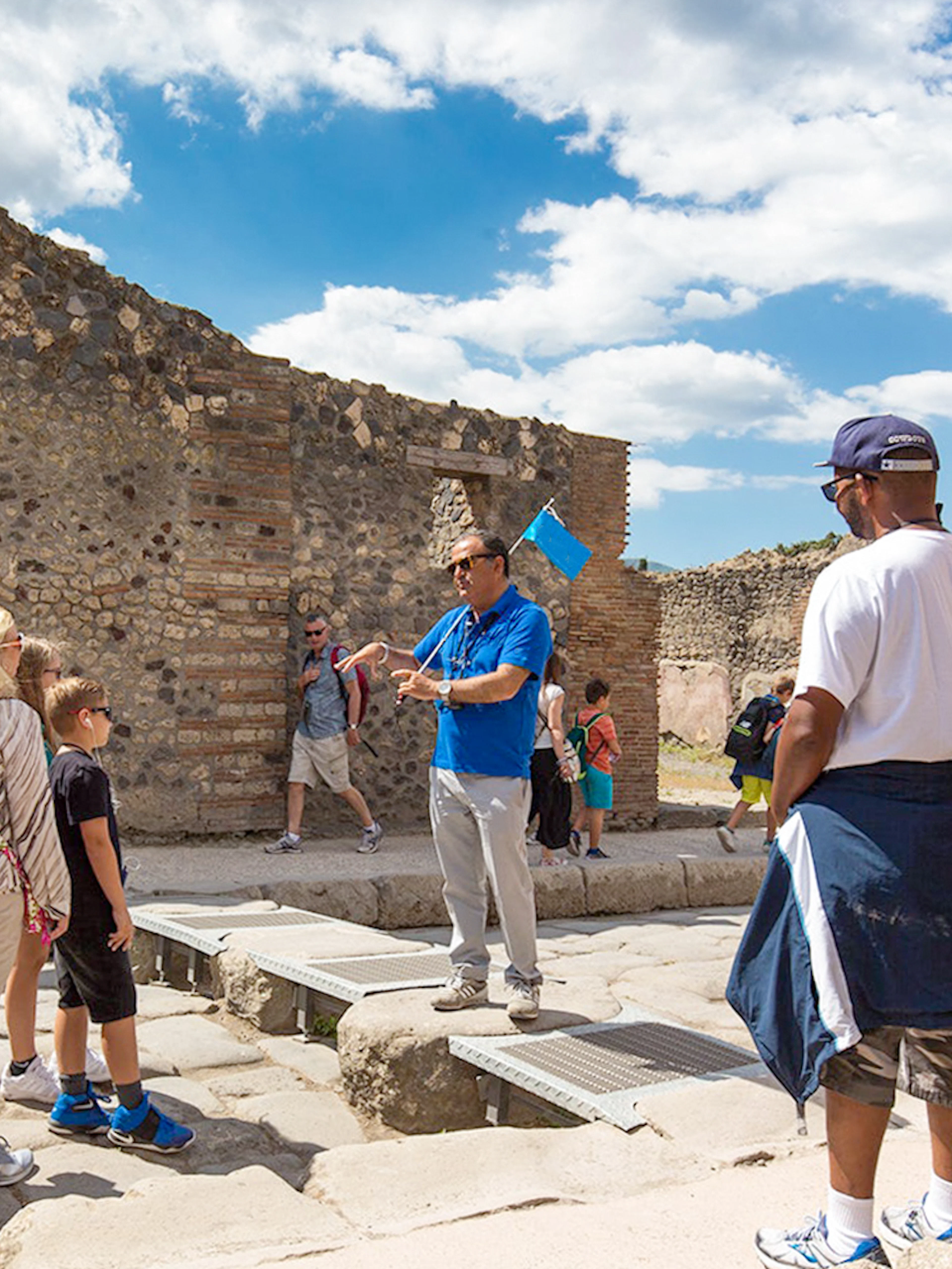 Visitors listening to a tour guide in Pompeii ruins, Italy.