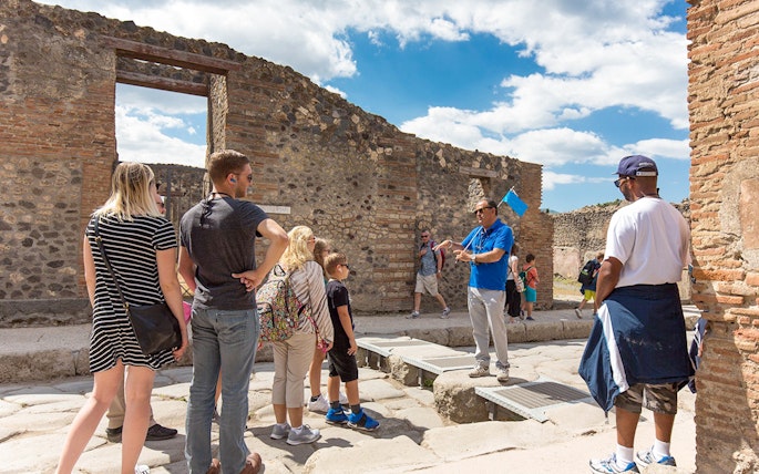Visitors listening to a tour guide in Pompeii ruins, Italy.