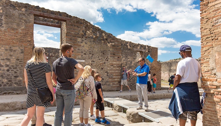 Visitors exploring Pompeii ruins with a tour guide, Naples, Italy.