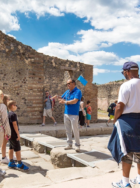 Visitors listening to a tour guide in Pompeii ruins, Italy.