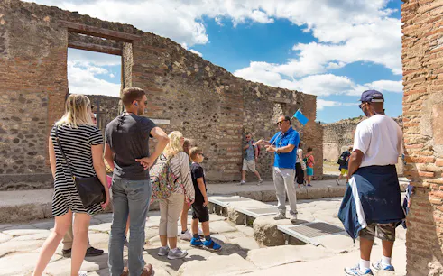 Visitors listening to a tour guide in Pompeii ruins, Italy.