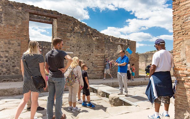 Visitors listening to a tour guide in Pompeii ruins, Italy.