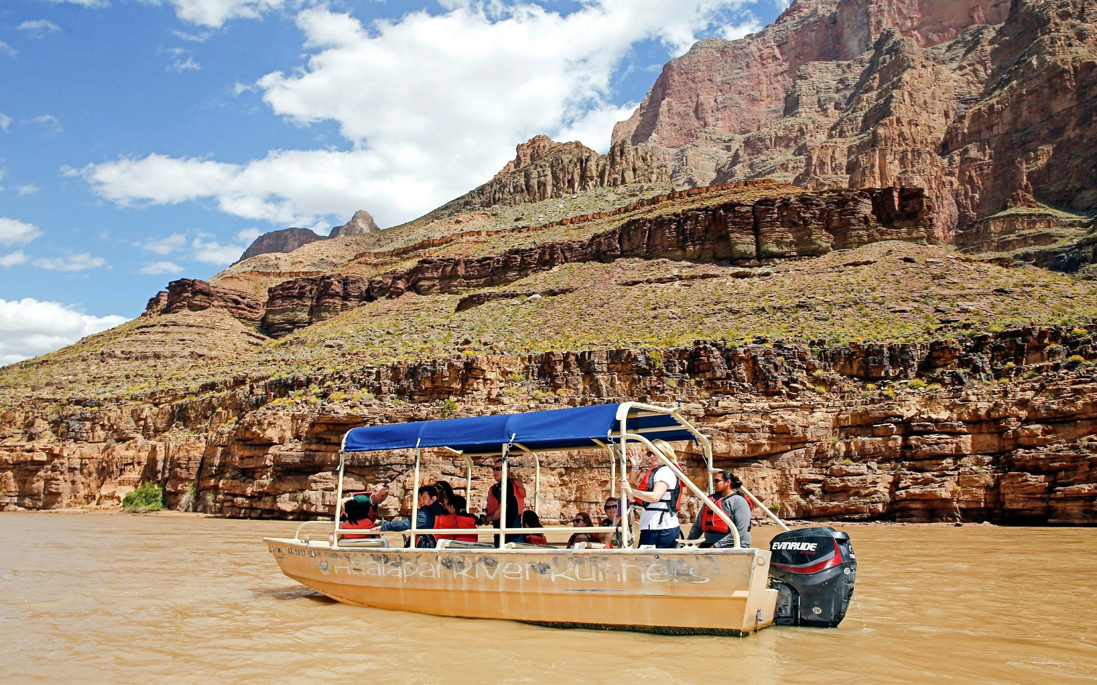 Boat ride on the Colorado River with tourists, Grand Canyon West Rim cliffs in background.