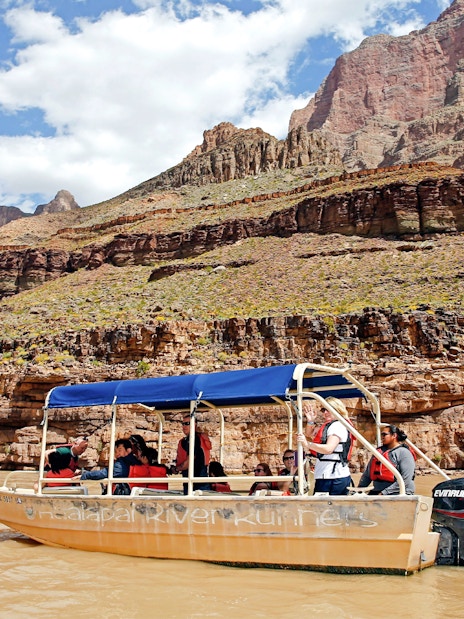 Boat ride on the Colorado River with tourists, Grand Canyon West Rim cliffs in background.