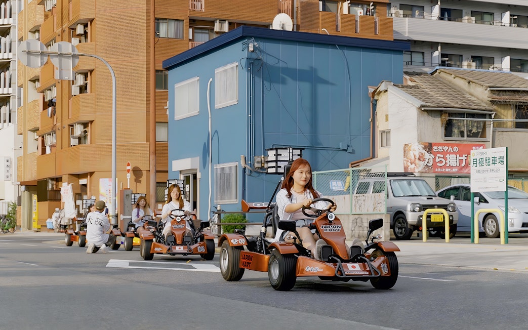 People driving go-karts on a street in Osaka during a 90-minute tour.