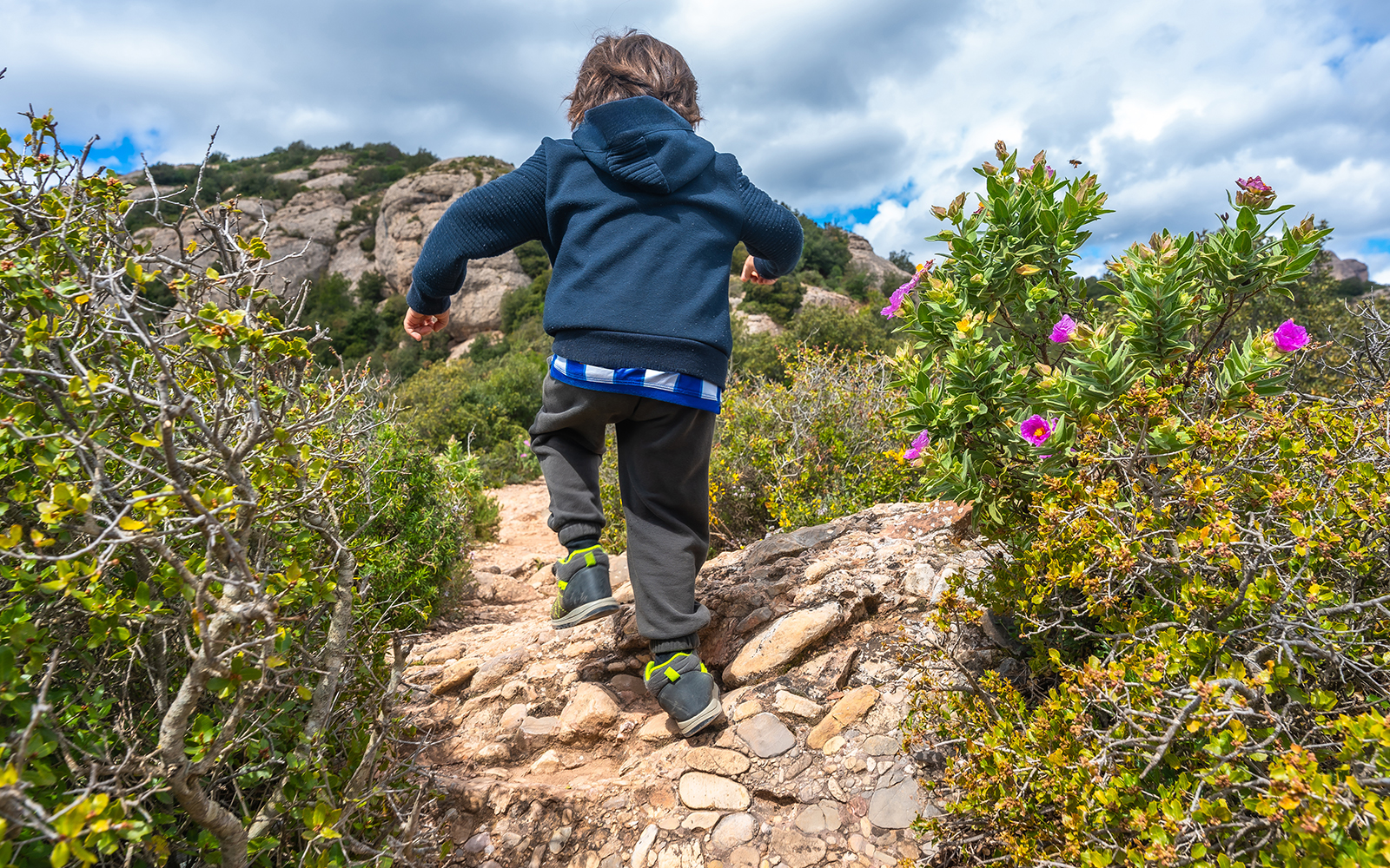 Child hiking on montserrat mountain path exploring nature during spring