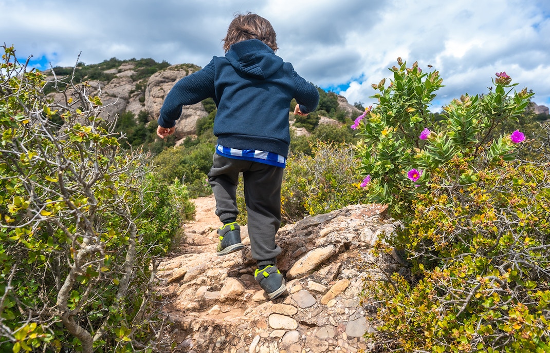 Child hiking on montserrat mountain path exploring nature during spring