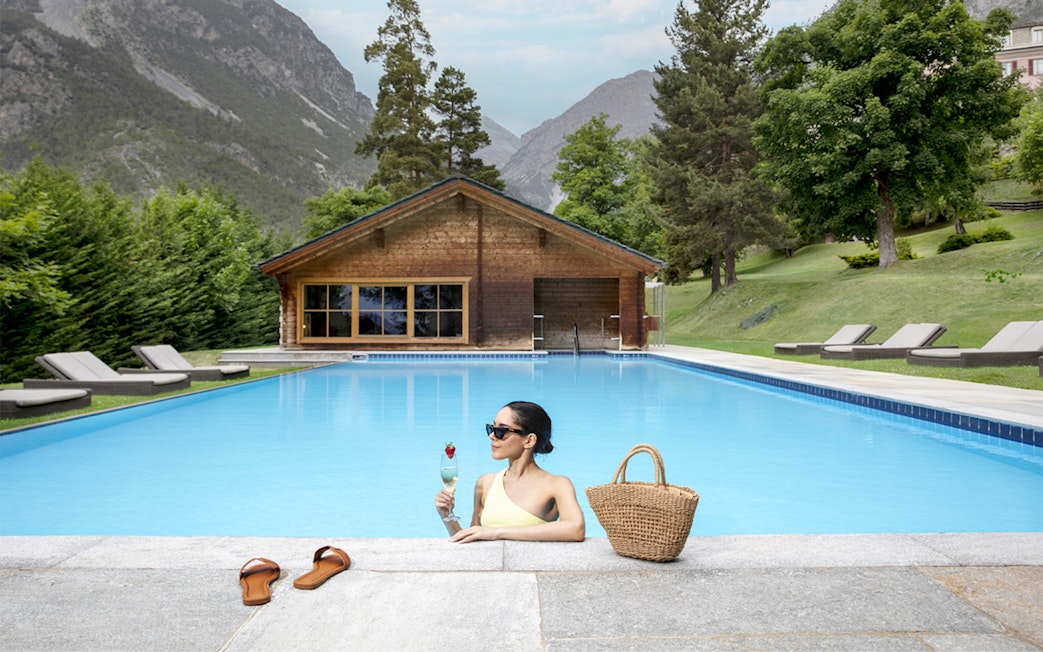 Person relaxing in a pool at QC Terme Bagni Nuovi di Bormio with mountain view.