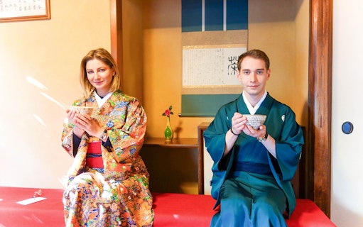 Couple in traditional Japanese attire enjoying tea ceremony indoors.