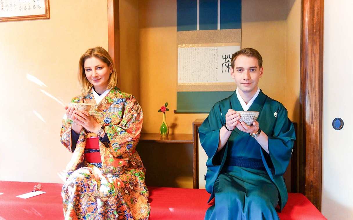 Couple in traditional Japanese attire enjoying tea ceremony indoors.