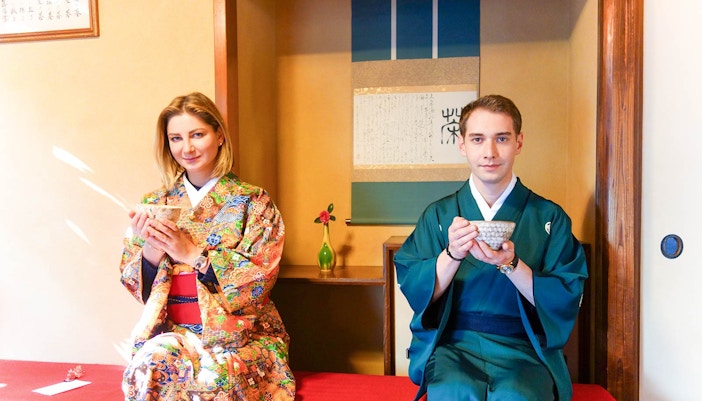 Couple in traditional Japanese attire enjoying tea ceremony indoors.