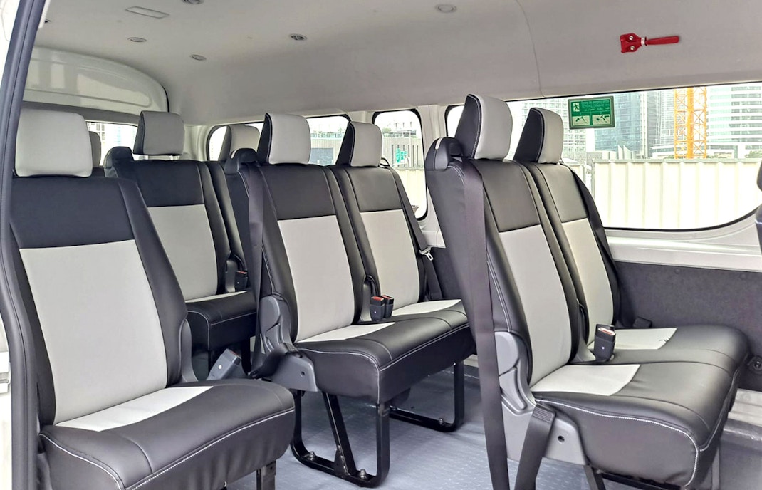 Shuttle bus interior with black and gray seats, Global Village.