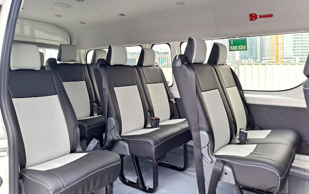 Shuttle bus interior with black and gray seats, Global Village.