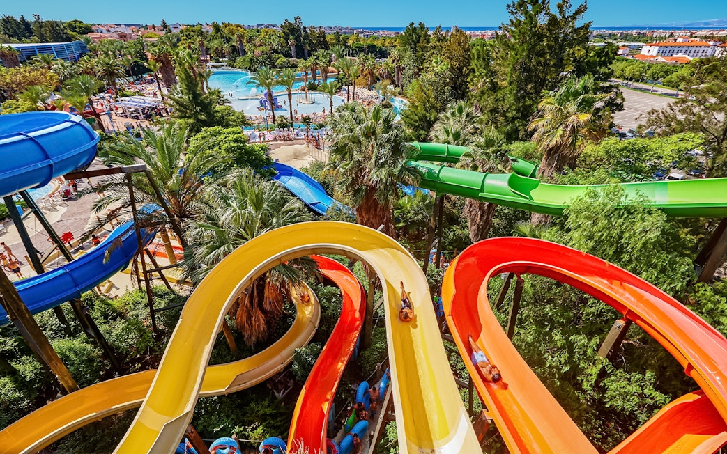 Colorful water slides at Caribe Aquatic Park with lush greenery and pools in the background.
