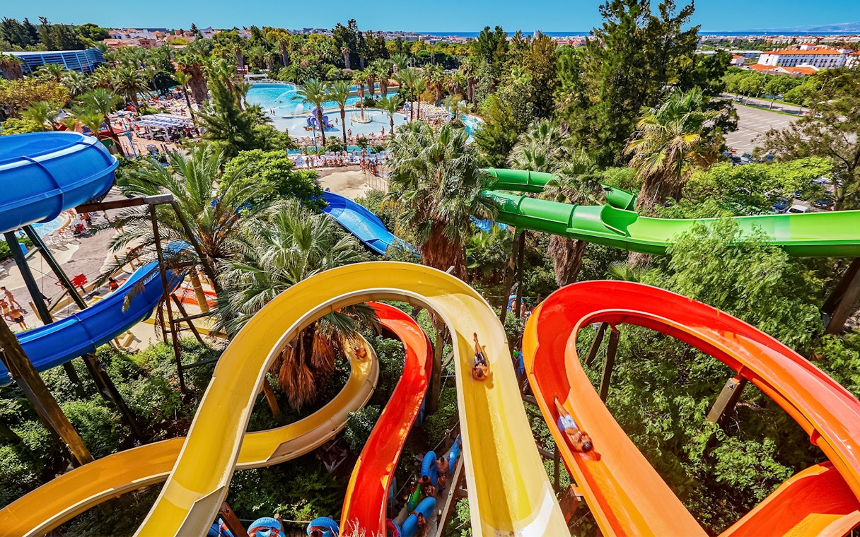 Colorful water slides at Caribe Aquatic Park with lush greenery and pools in the background.