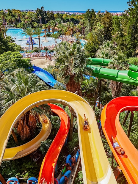 Colorful water slides at Caribe Aquatic Park with lush greenery and pools in the background.