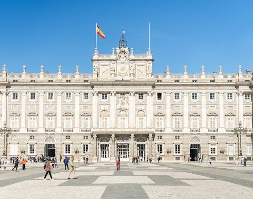Royal Palace of Madrid exterior with ornate architecture and tourists exploring the grounds.