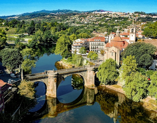 Skyview of Saint Gonçalo Bridge and Church in Amarante, Portugal, surrounded by lush greenery.
