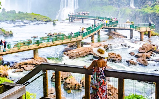 Visitor admiring Iguazu Falls from a viewing platform in Brazil.