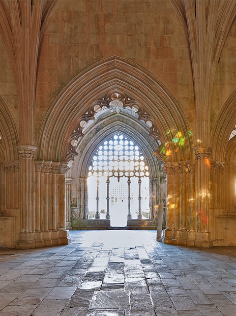Gothic arches inside Lisbon monastery with a cat sitting on the stone floor.