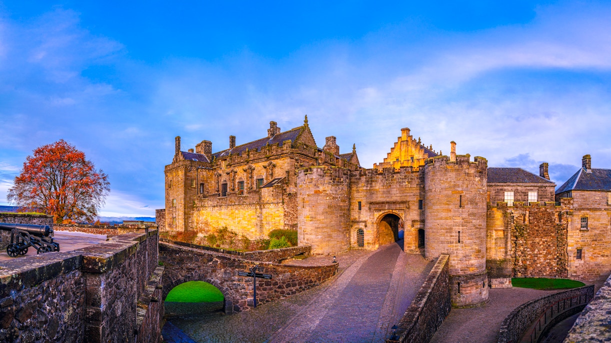 Stirling Castle entrance with stone walls and autumn tree in Scotland, United Kingdom.