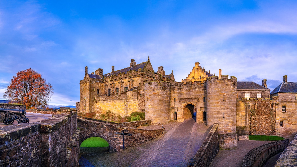 Stirling Castle entrance with stone walls and autumn tree in Scotland, United Kingdom.