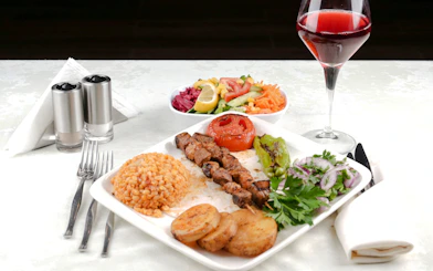 Grilled meat skewers with rice, vegetables, and wine on Bosphorus dinner cruise.