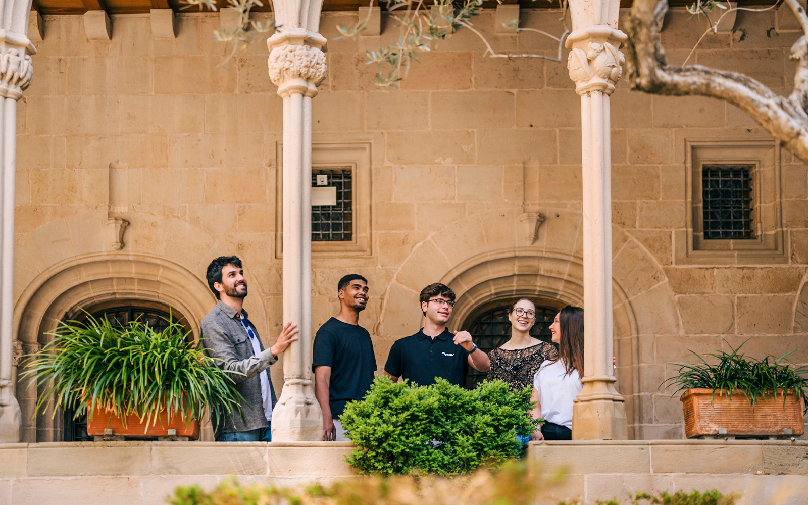 Tourists with guide exploring Montserrat Monastery courtyard.