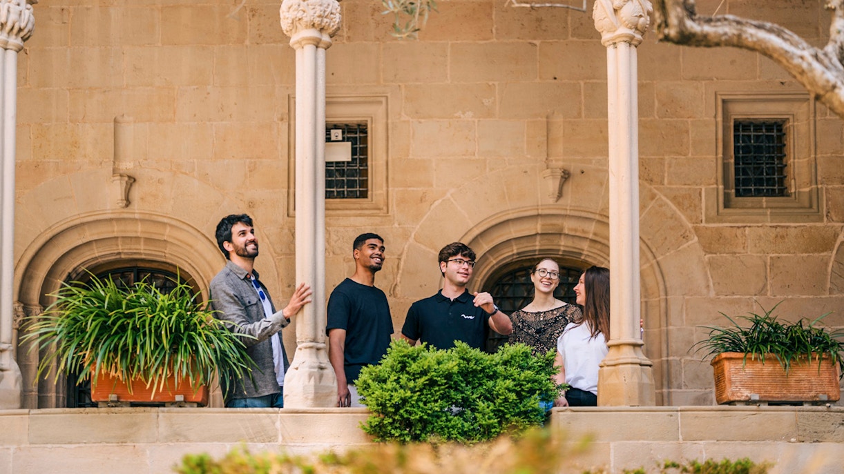 Tourists with guide exploring Montserrat Monastery courtyard.