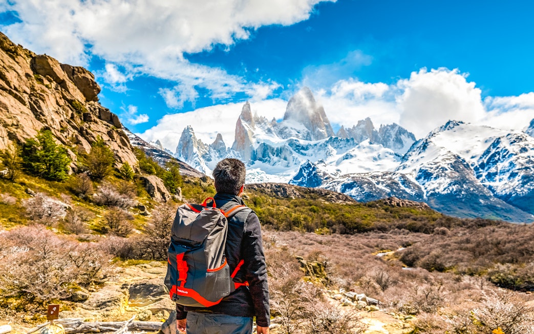 Tourist with backpack admiring snow-capped mountains in Patagonia.