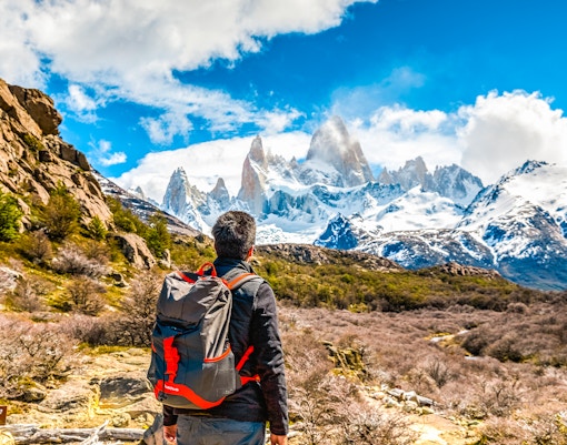 Tourist with backpack admiring snow-capped mountains in Patagonia.