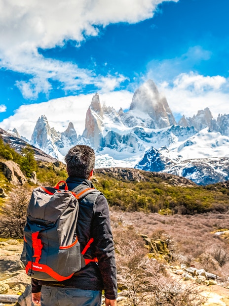 Tourist with backpack admiring snow-capped mountains in Patagonia.
