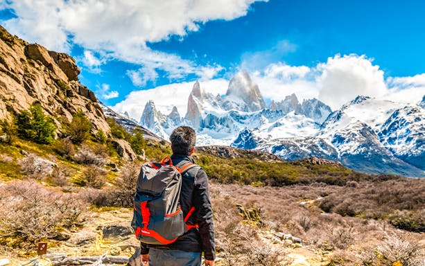 Tourist with backpack admiring snow-capped mountains in Patagonia.