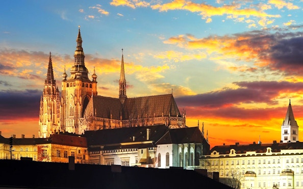 Prague Castle exterior at sunset with vibrant sky.