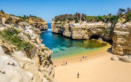 Great Ocean Road's Loch Ard Gorge with visitors on sandy beach, Melbourne tour.