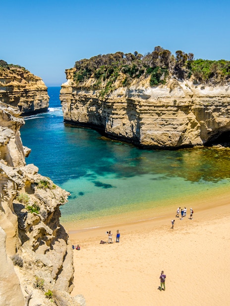 Great Ocean Road's Loch Ard Gorge with visitors on sandy beach, Melbourne tour.