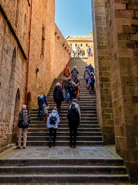 Tourists ascending stone steps in Mont Saint Michel, France.