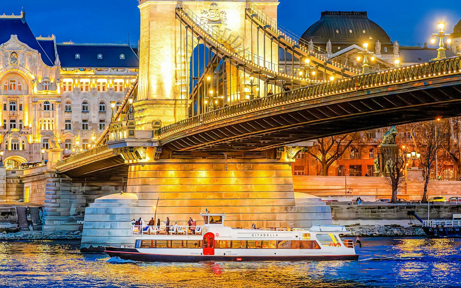 Budapest Danube River nighttime cruise with illuminated cityscape and historic buildings.